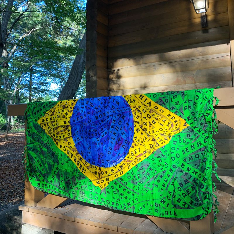 Brazil flag Fitinha do Bonfim sarong displayed outdoors on a wooden deck — Fashion Brazil