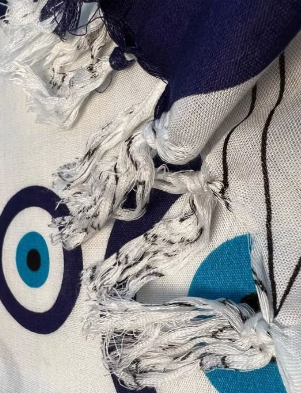 Close-up of mandala evil eye sarong with tassels and a blue and white circular pattern.