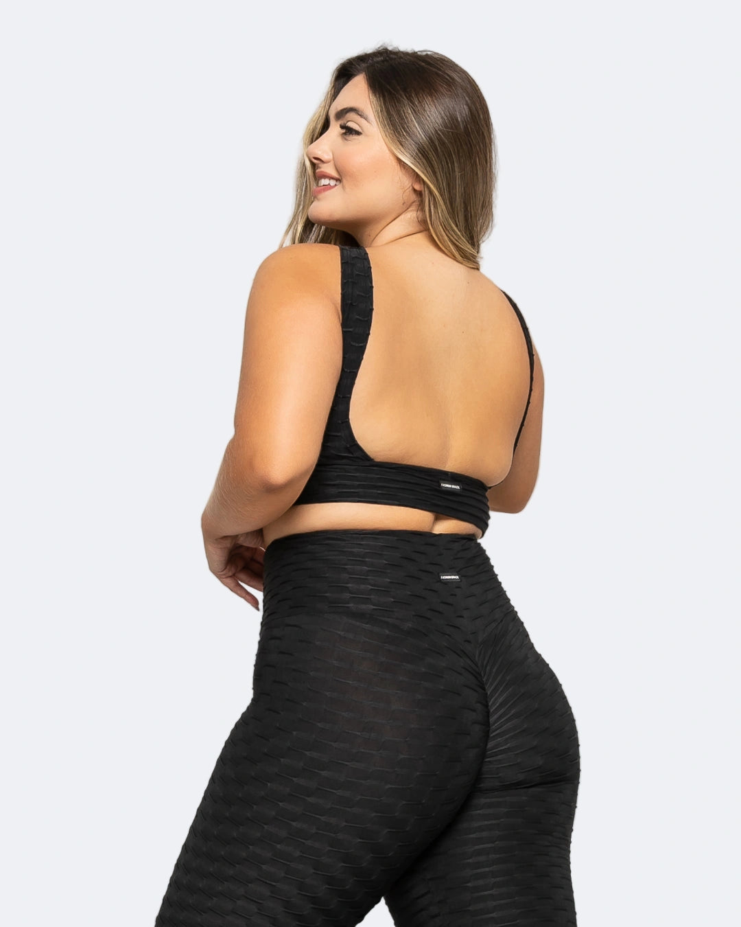 Woman wearing a black sports bra and leggings on a white background