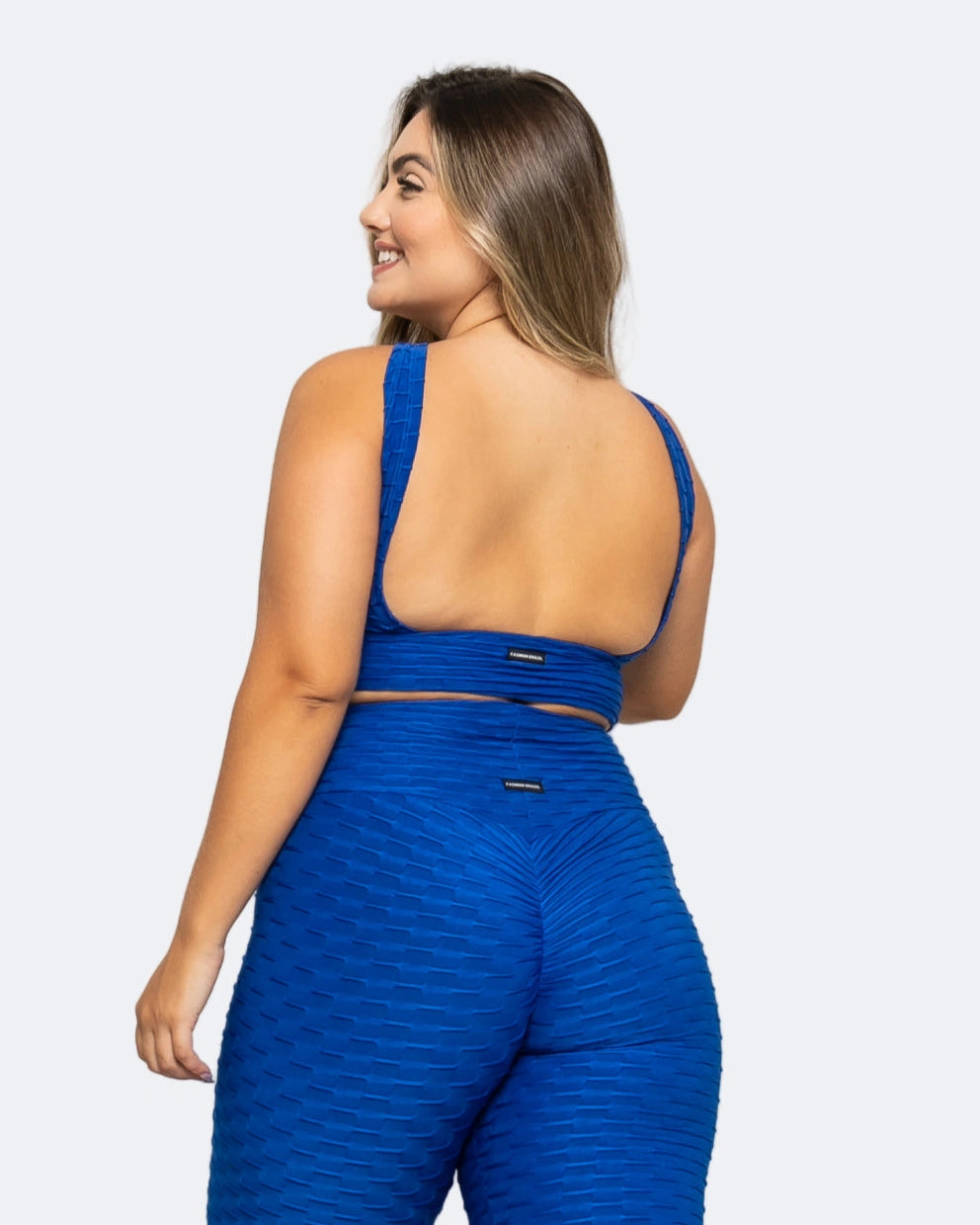 Woman wearing a blue sports bra and leggings set on a white background