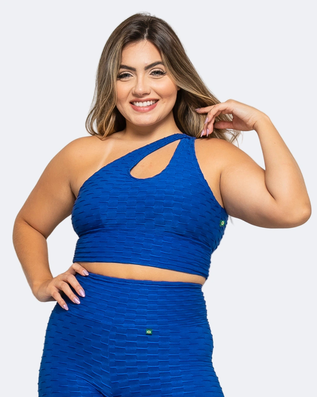 A woman wearing a blue sports bra with a textured fabric, featuring a halter neck and crisscross strap design.