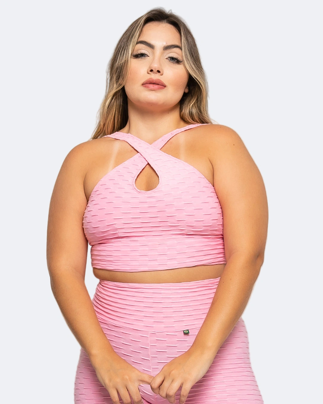 Woman wearing a pink pleated top and skirt set on a light gray background