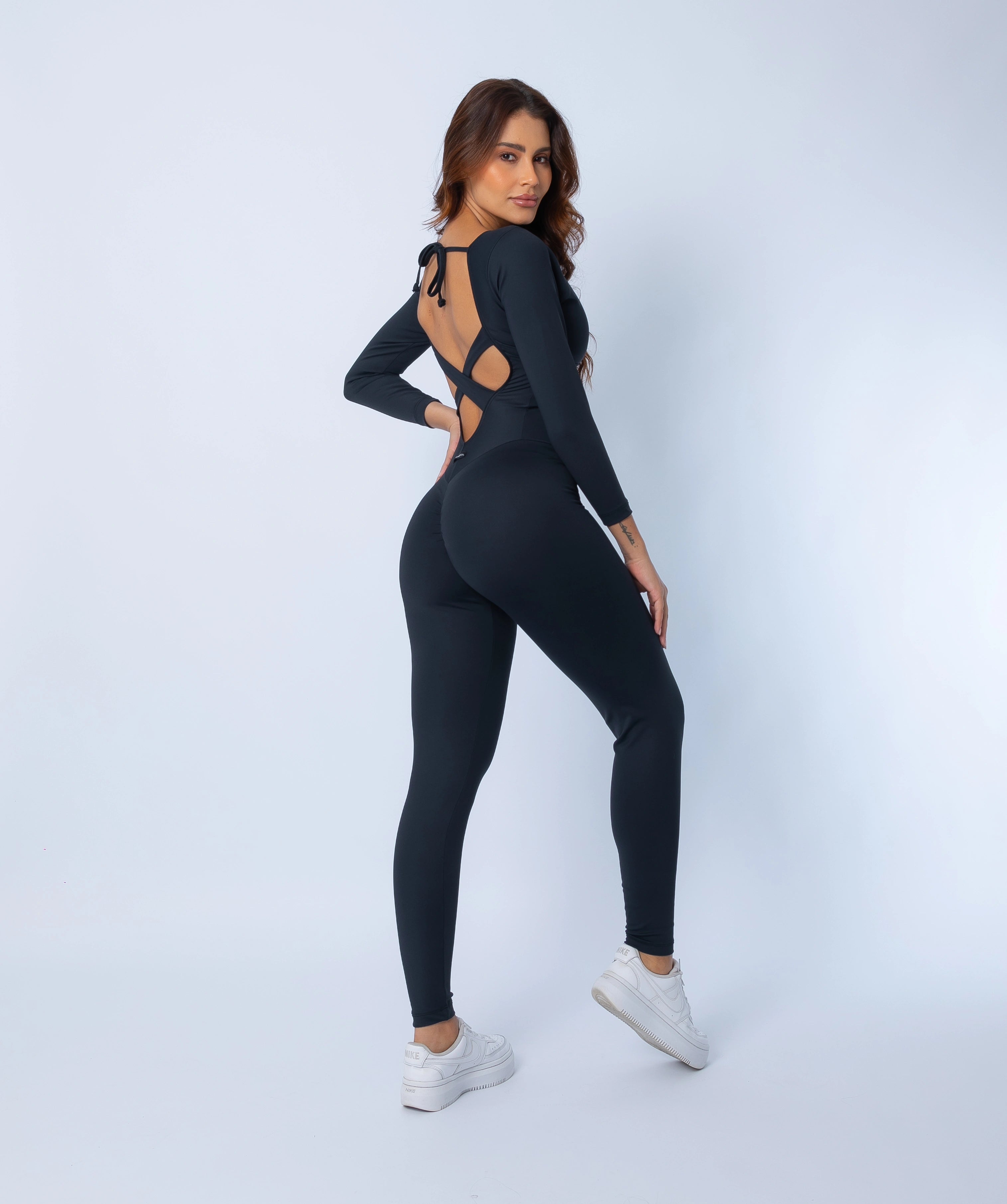 Fashion Brazil Elevate Long Sleeve Jumpsuit back-side view, showing criss-cross open back straps, tie closure, and sculpting compression fit with long sleeves.