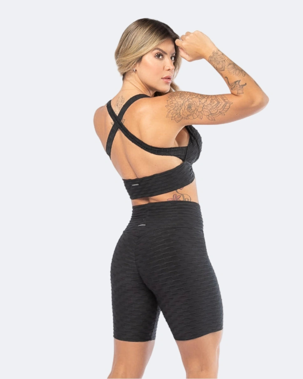 Woman wearing a black sports bra and high-waisted shorts on a white background