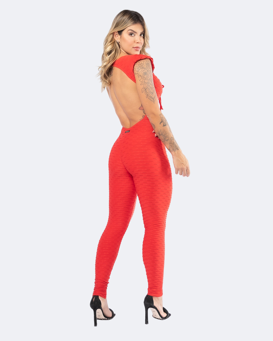 Woman wearing a red jumpsuit with a open back design.