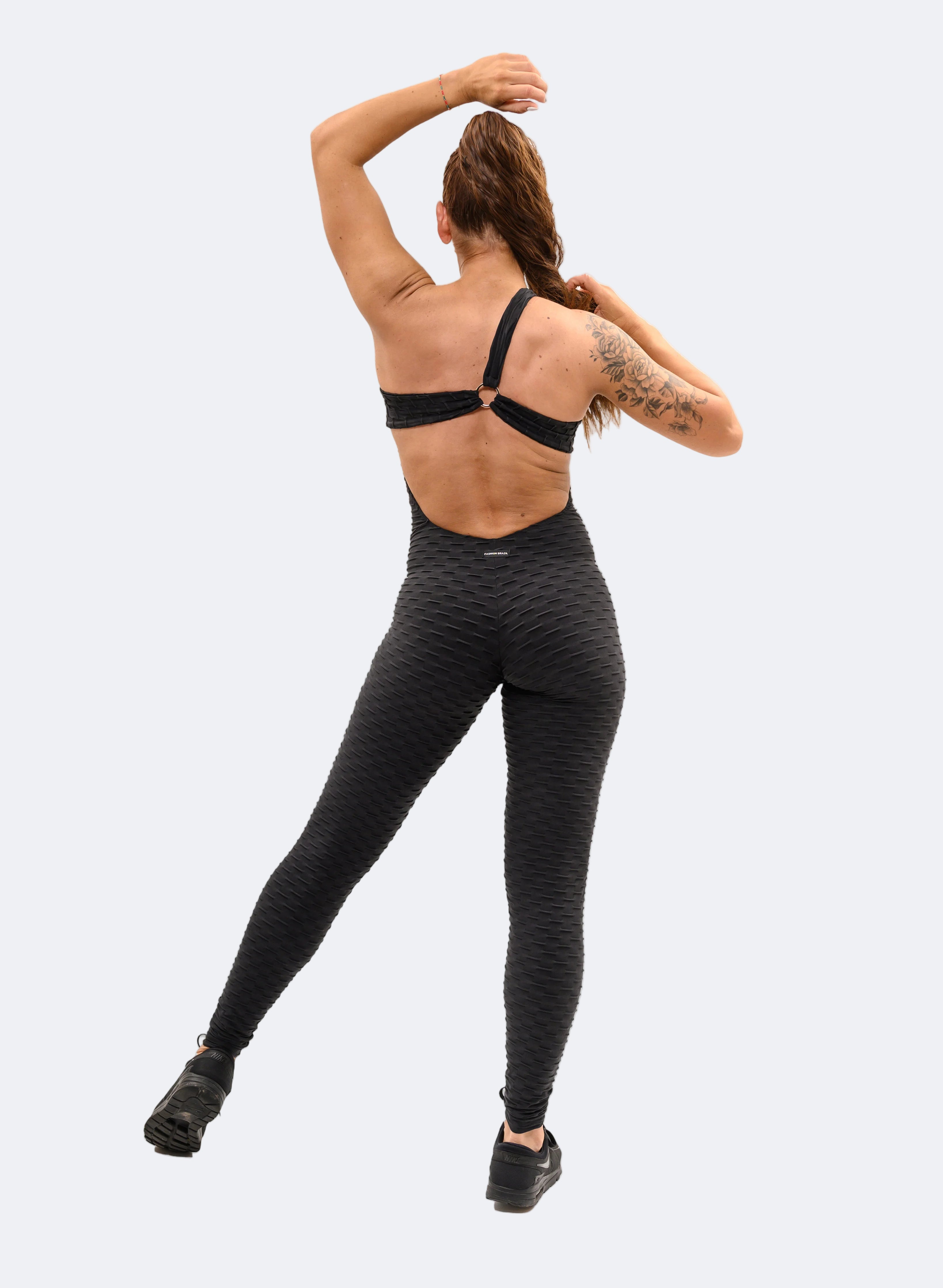 Person wearing black athletic leggings and sports bra on a white background