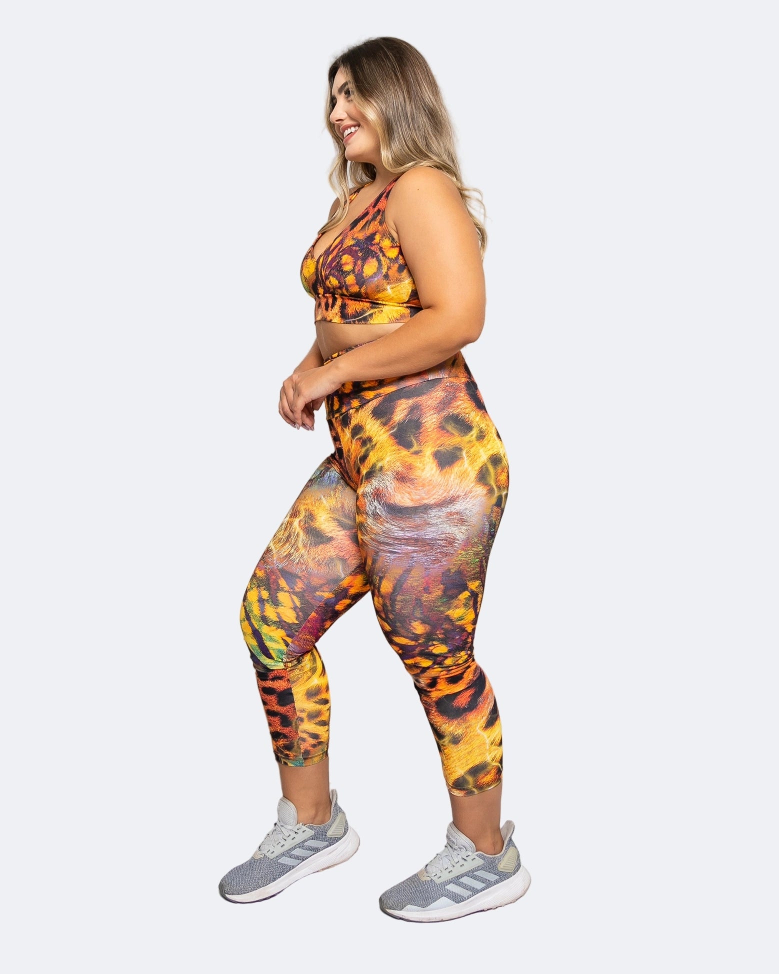 Woman wearing a colorful safari animal print 7/8 leggings and sports bra on a white background