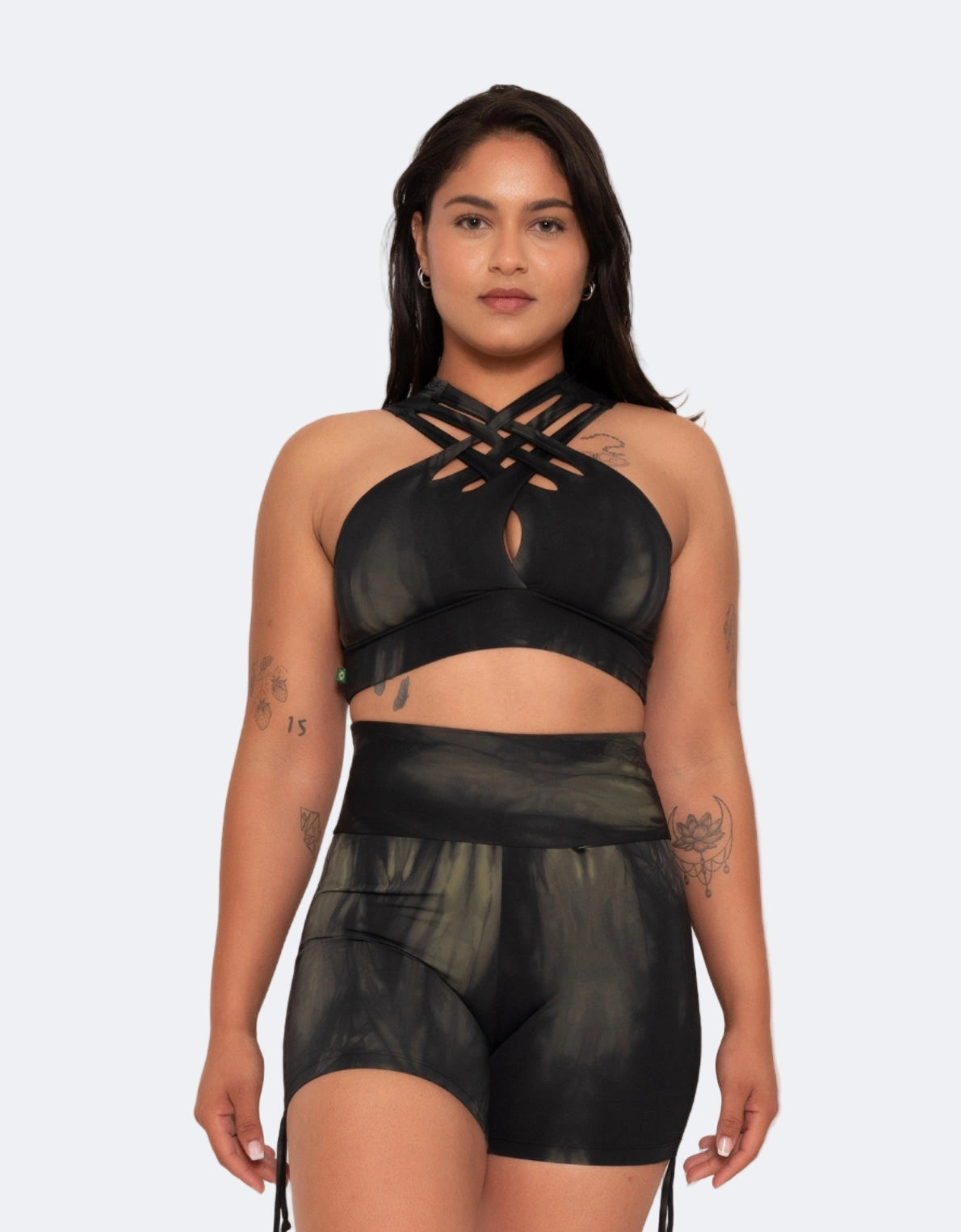 Model wears black and dark green tie-dye active crop with a crisscross front and caped back design, made of smooth, stretchy fabric.