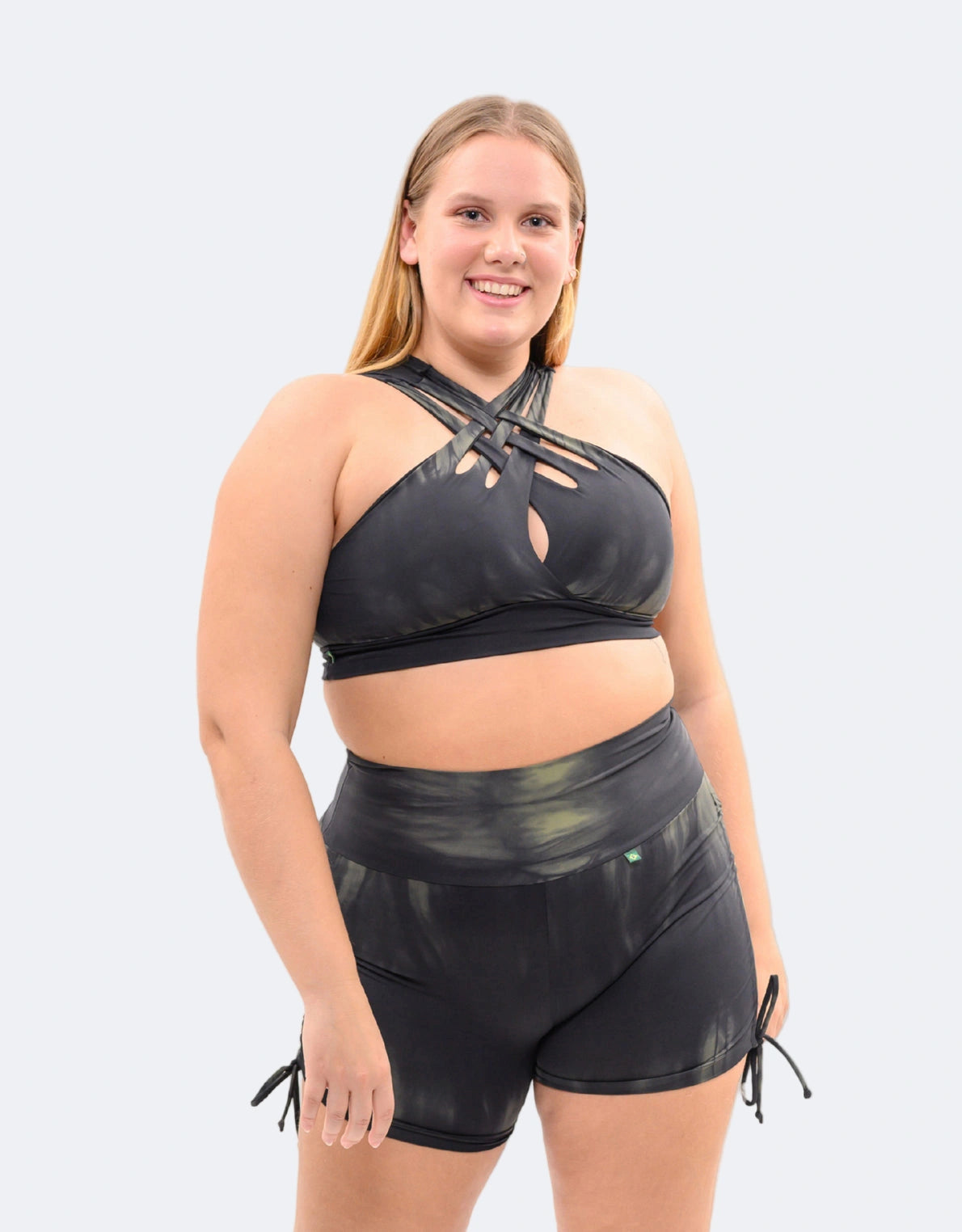 Curvy model in the Black Ivy Tie-Dye active set, featuring tie-side shorts and matching sports crop.