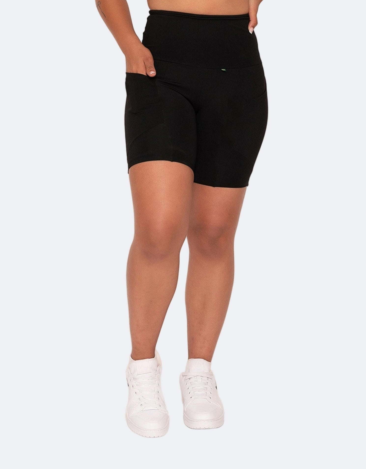 model wears mid length black high waisted shorts with side pockets. 