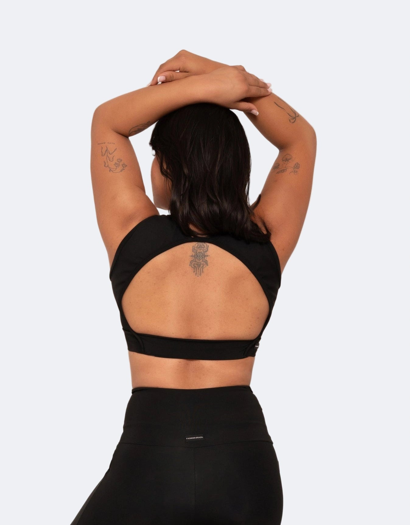 Person wearing a black sports bra and leggings on a light gray background