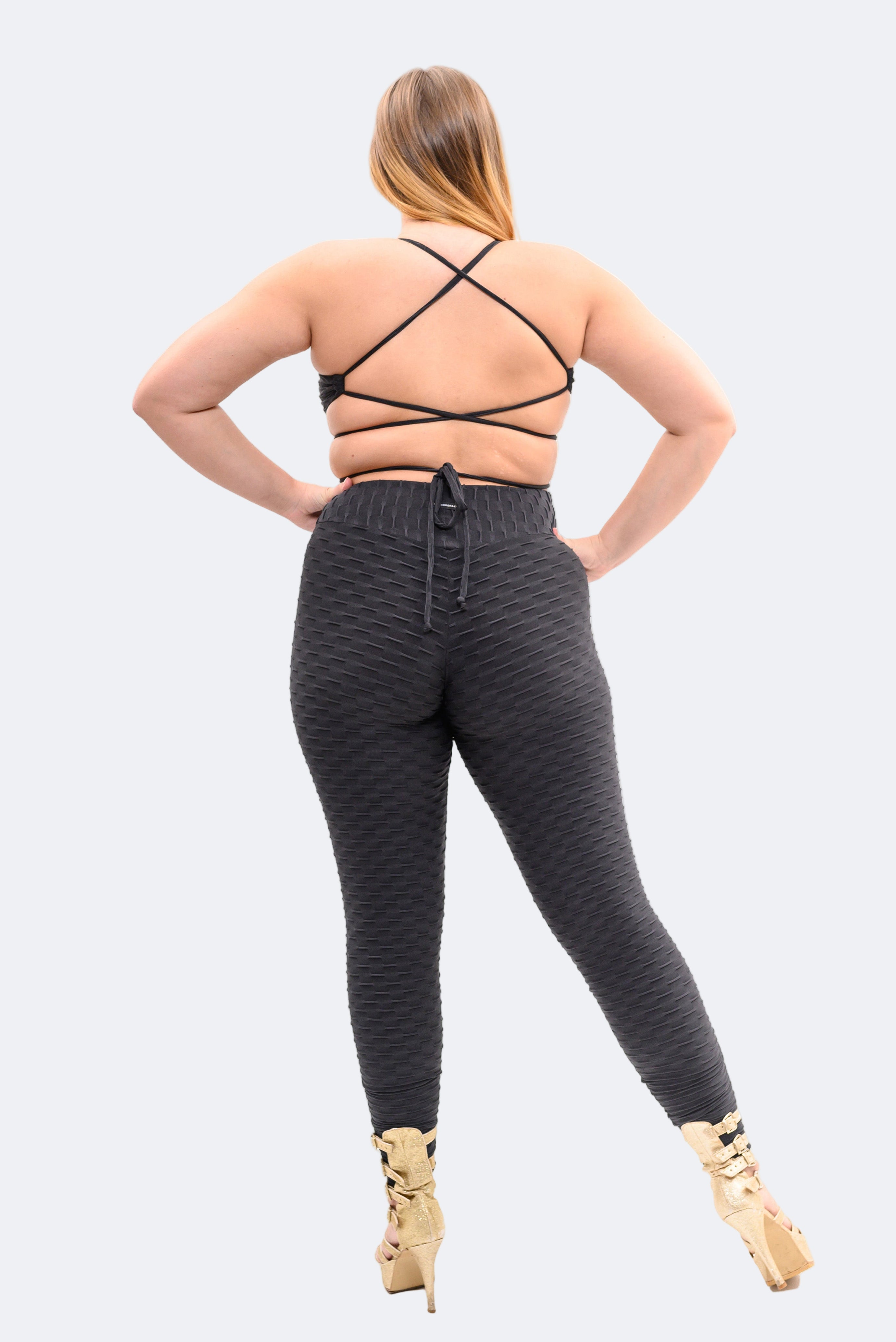 Person wearing black jumpsuit with a black strappy top on a white background