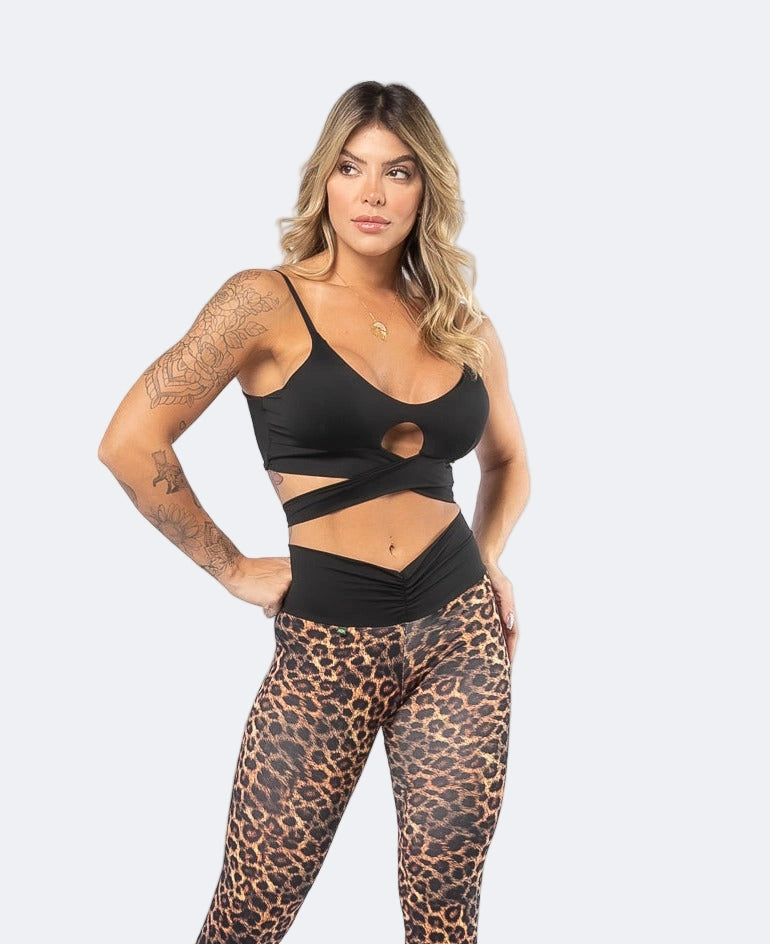 A woman wearing a tie-front active crop top and matching leggings with a leopard print design.