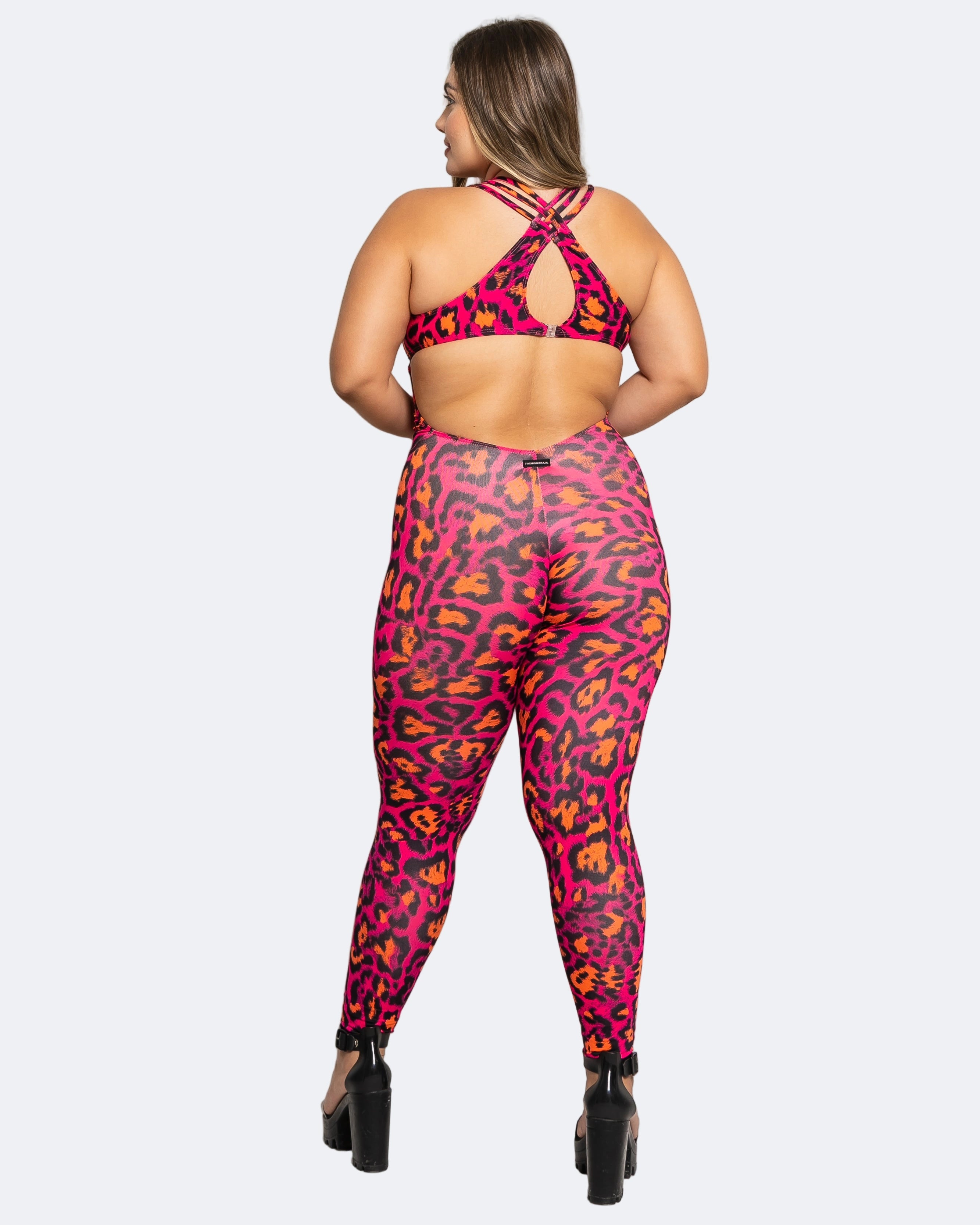 Woman wearing a pink and orange leopard print sports bra and leggings set on a white background