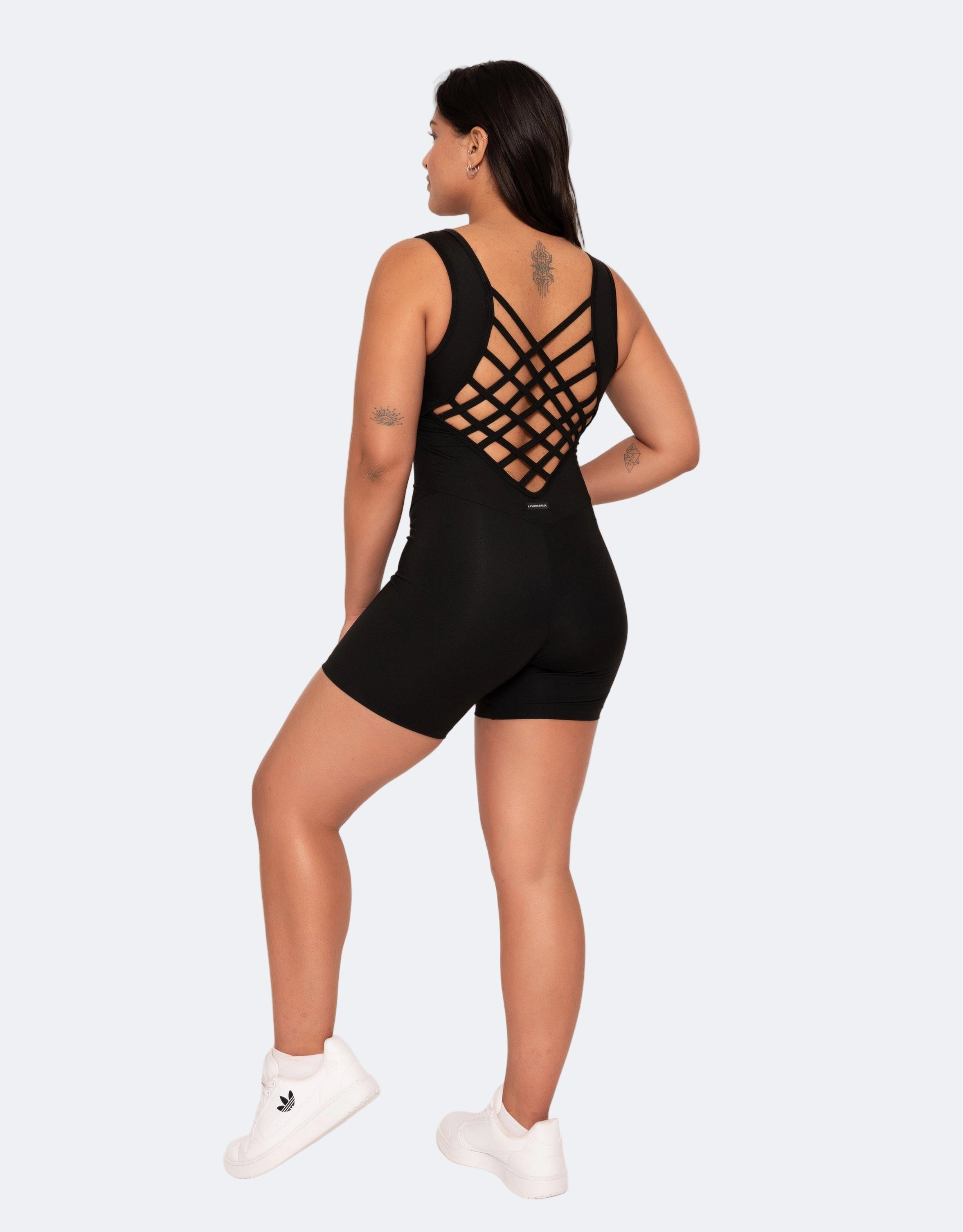Woman wearing a black romper with cut-out design on a white background