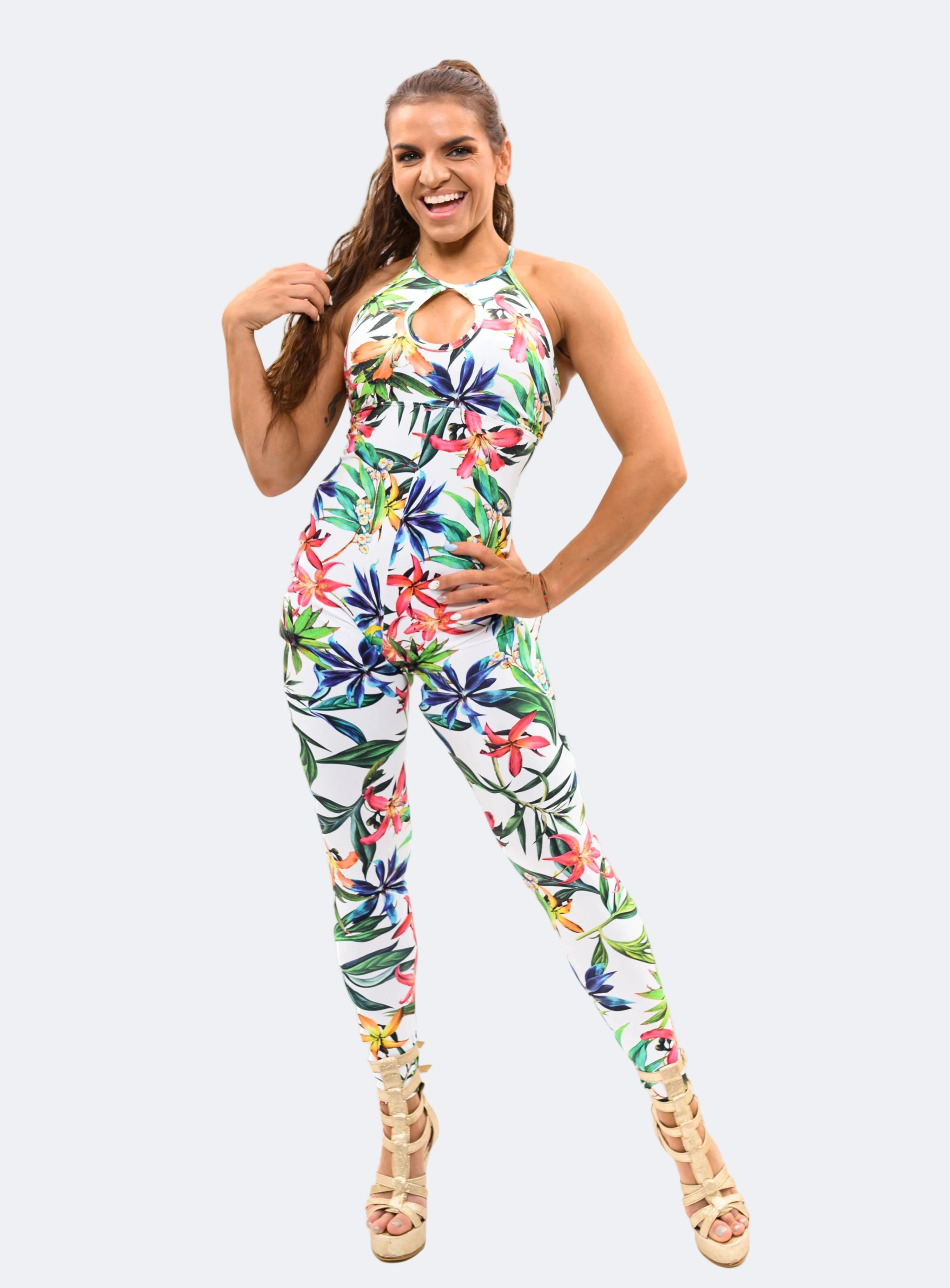 A female model wearing a multicolored floral jumpsuit with a tie-dye pattern, posing against a white background.
