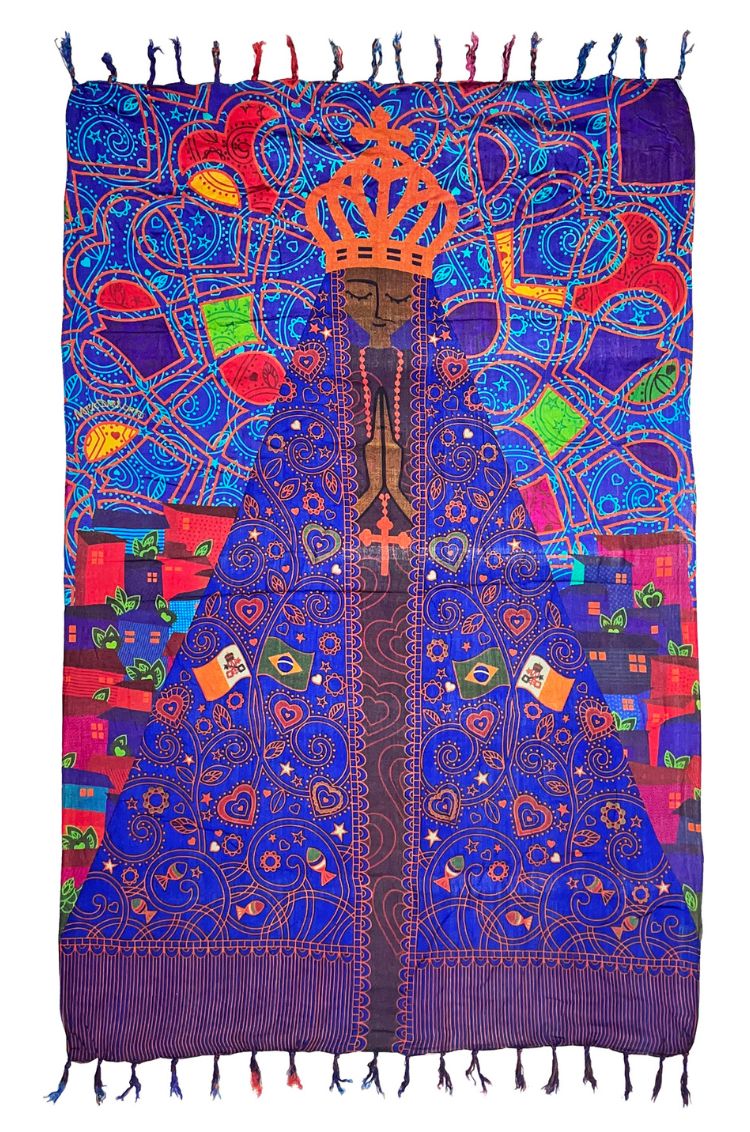 The design features a depiction of Our Lady of Aparecida, shown with dark skin, a golden crown, and hands clasped in prayer, wearing an intricately patterned blue and gold cloak. 