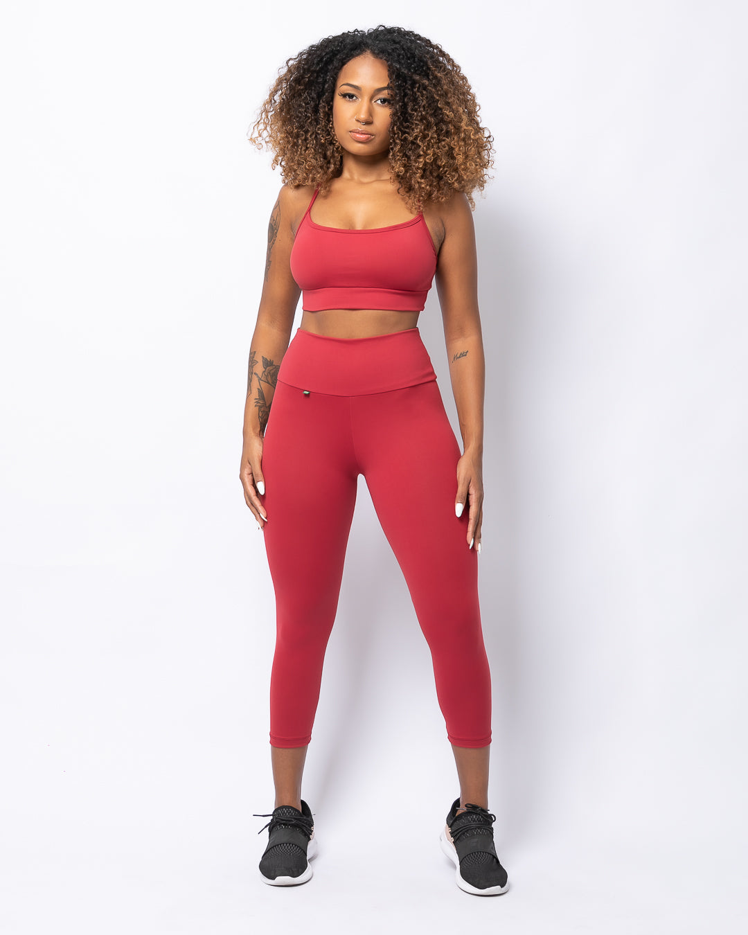 A model wearing a matching set of bordeaux red high-waisted leggings and a sports crop top.