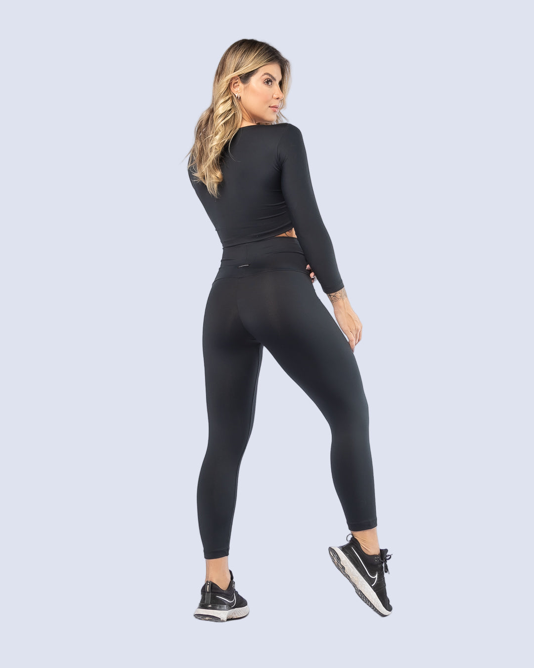 Woman wearing a black athletic outfit on a light gray background